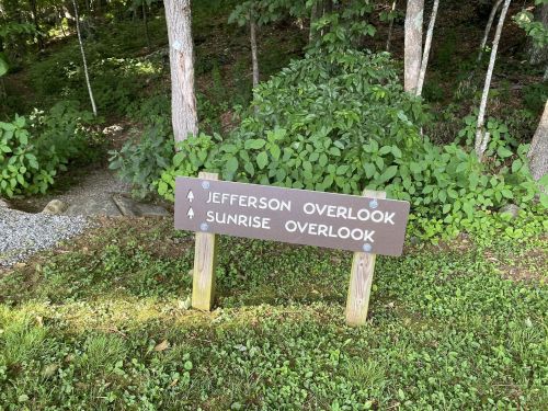 A wooden signpost in a forest, indicating directions to Jefferson Overlook and Sunrise Overlook.