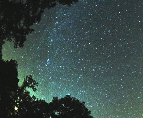 A starry night sky filled with twinkling stars and a bright meteor streaking across the scene.