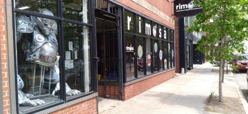 Storefront of Rimosa featuring large metallic sculpture in window and a sidewalk view of the street.