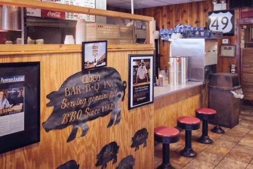 Interior of Abe's Bar-B-Q, featuring wooden walls, BBQ memorabilia, and red stools at a counter.