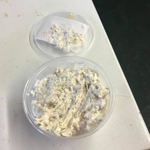 A clear plastic container with a lid, containing a creamy, textured spread or dip.