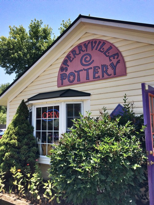 A charming pottery shop with a colorful sign reading "Sperryville Pottery" and an "Open" neon sign in the window.