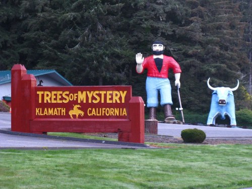 A large statue of a lumberjack waves next to a blue bull at the Trees of Mystery in Klamath, California.