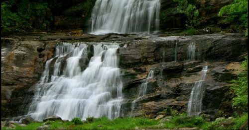 A serene waterfall cascading over rocky cliffs, surrounded by lush greenery and a tranquil landscape.