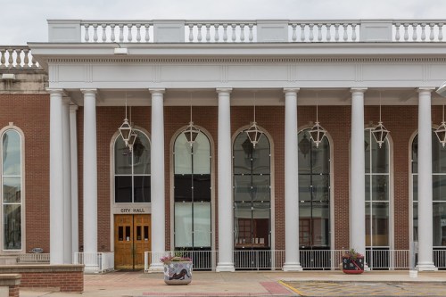 Front view of a city hall building featuring tall columns, large windows, and decorative lanterns.