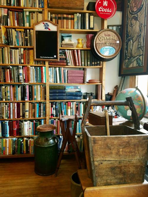A cozy room filled with bookshelves, vintage items, and a wooden crate, creating a warm, nostalgic atmosphere.