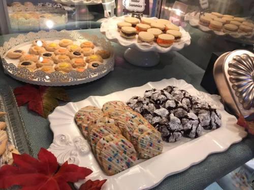 A display of assorted cookies, including colorful spritz cookies and chocolate crinkle cookies, on elegant platters.
