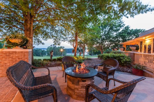 Cozy outdoor seating area with a fire pit surrounded by trees and a scenic view at dusk.