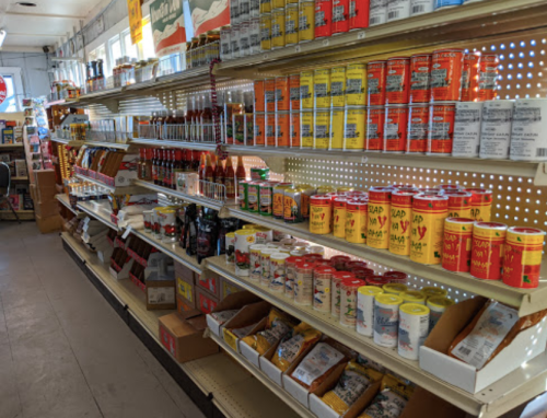 A grocery store aisle filled with various canned goods, sauces, and packaged items on shelves.