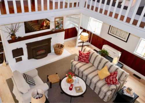 Cozy living room with a striped sofa, armchair, coffee table, and a fireplace, featuring warm lighting and decorative accents.