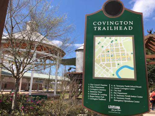 Signpost for Covington Trailhead, featuring a map and information about local facilities in Covington, Louisiana.