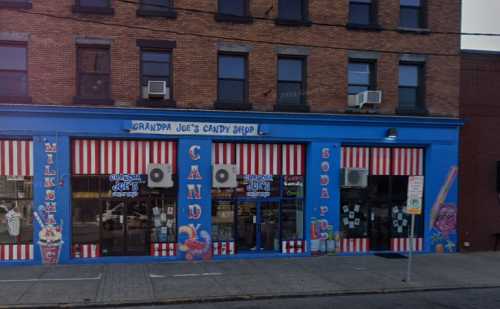 Colorful storefront of Grandpa Joe's Candy Shop, featuring striped awnings and large candy-themed decorations.