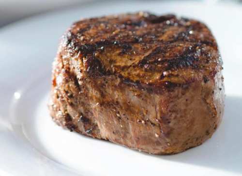 A perfectly grilled steak on a white plate, showcasing a juicy, tender texture with grill marks.