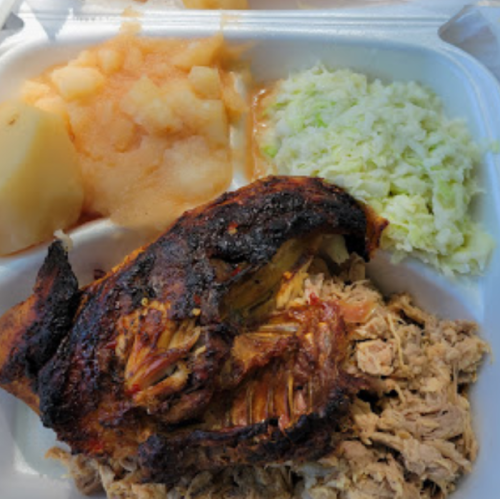 A takeout container with grilled chicken, shredded meat, coleslaw, applesauce, and a potato.