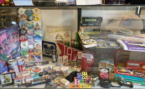 A display case filled with vintage memorabilia, including pins, toys, games, and various collectibles.