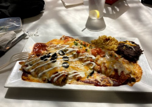 A plate of enchiladas topped with cheese, olives, and sauce, served with rice and beans on the side.