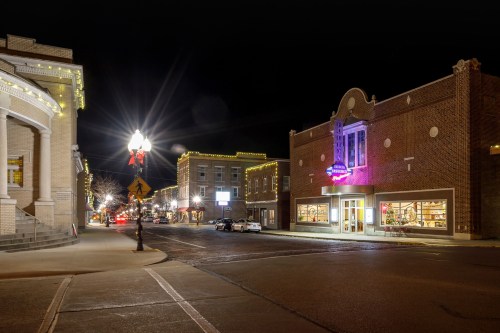 A charming downtown street at night, featuring illuminated buildings and festive lights.