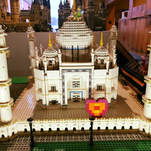 A detailed Lego model of a palace with a heart-shaped decoration in front, set in a colorful display.