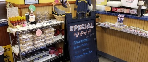 A café display featuring a sign for special blueberry pastries and a table with baked goods and condiments.