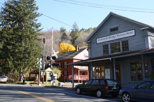 A quaint street scene featuring the Cornwall Bridge Pottery Store, surrounded by trees and autumn colors.