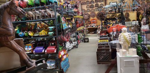 A colorful collection of vintage toys and decorations displayed on shelves in a spacious indoor market.