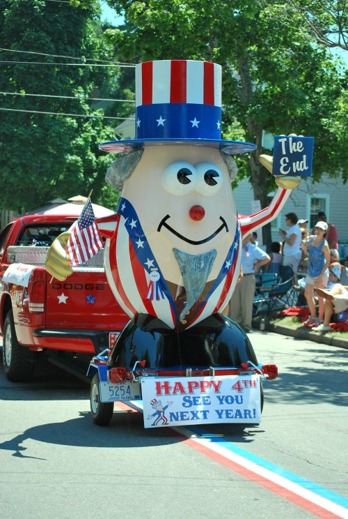 A festive parade float featuring a large, smiling Uncle Sam figure waving, with a sign reading "The End" and a "Happy 4th" banner.