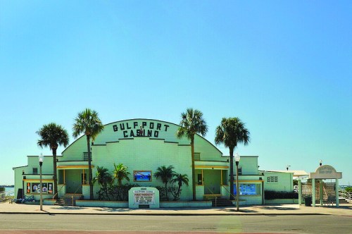 Gulfport Casino building with palm trees, clear blue sky, and signage in front.