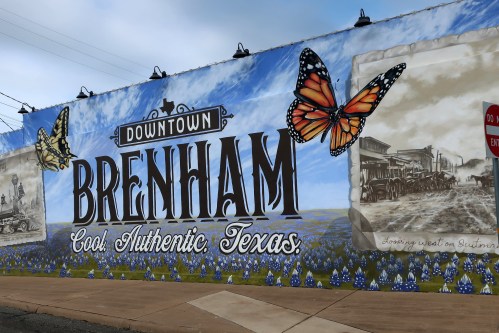 Colorful mural in Brenham, Texas, featuring butterflies and historical images, promoting the town's charm and authenticity.