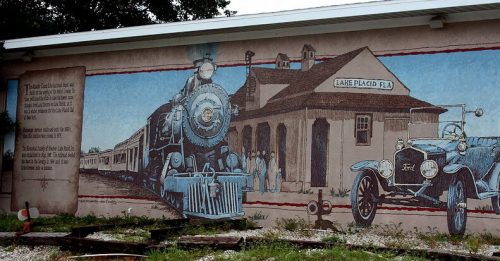 Mural depicting a vintage steam train and an old car outside a train station in Lake Placid, Florida.
