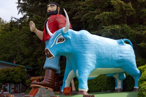 A large statue of a man with a beard and a blue bull, surrounded by trees and greenery.