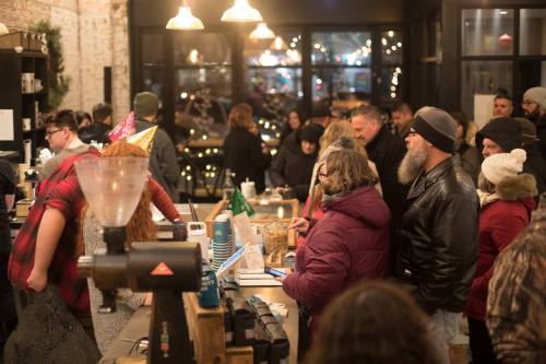 A busy café scene with a line of customers at the counter, festive decorations, and warm lighting in the background.