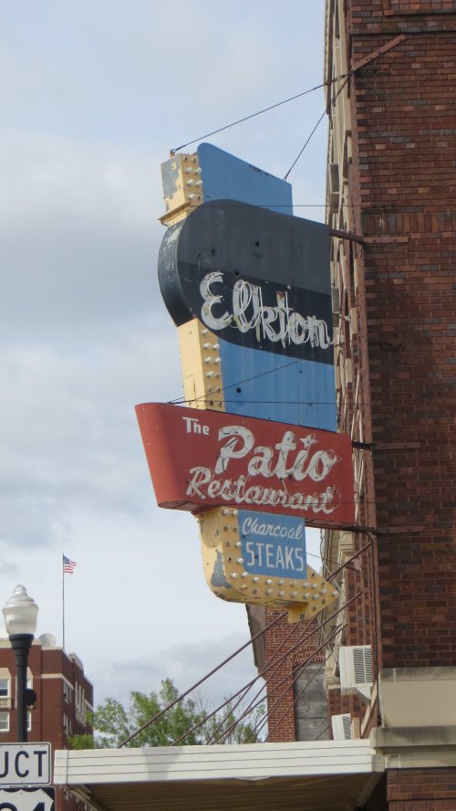 Vintage sign for "Elkton Patio Restaurant" featuring "Charcoal Steaks," set against a cloudy sky.