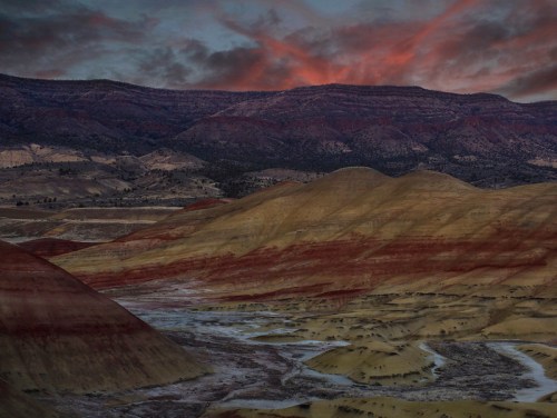 Vibrant hills of the Painted Desert at sunset, with colorful layers and a dramatic sky in the background.