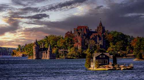 A scenic view of a castle on an island, surrounded by water and autumn foliage under a dramatic sky.