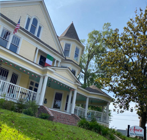 A charming yellow house with a tower, featuring an Italian flag and a sign for "Amore Italian Ristorante."