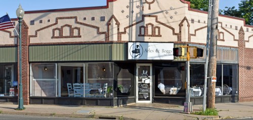 A charming restaurant exterior with large windows, decorative brickwork, and a sign reading "Arles & Boggs."