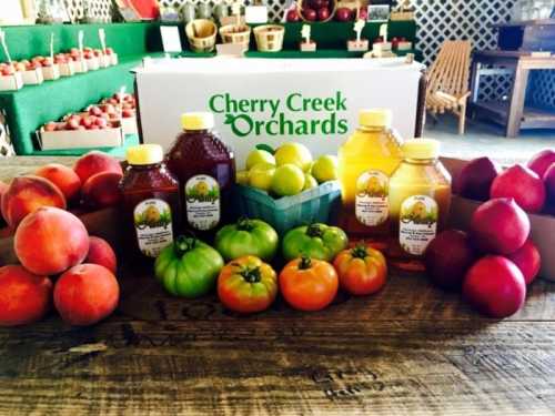 A variety of fresh fruits and honey jars displayed on a wooden table at Cherry Creek Orchards.