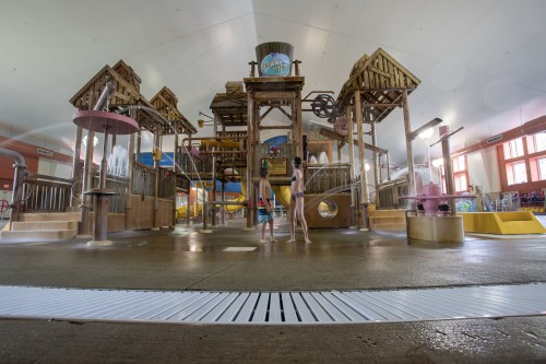 A colorful indoor water play area with slides, water features, and children enjoying the attractions.