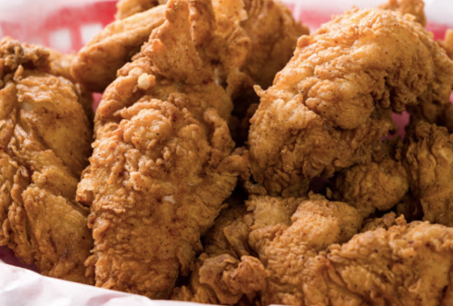 A close-up of crispy, golden-brown fried chicken pieces in a basket.