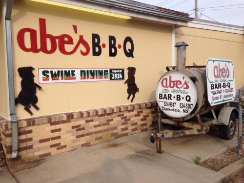 Sign for Abe's BBQ featuring "Swine Dining" and a trailer outside the restaurant in Clarksdale, MS.