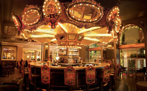 A beautifully lit bar with ornate mirrors and colorful decorations, surrounded by elegant seating.