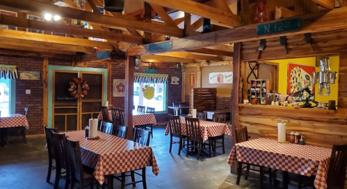 Cozy restaurant interior with checkered tablecloths, wooden beams, and a welcoming atmosphere.