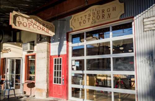 Exterior of the Pittsburgh Popcorn Co. with a red door and large windows, showcasing a welcoming storefront.