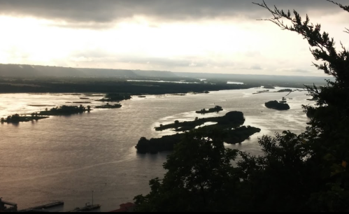 A scenic view of a winding river surrounded by islands and lush greenery under a cloudy sky.