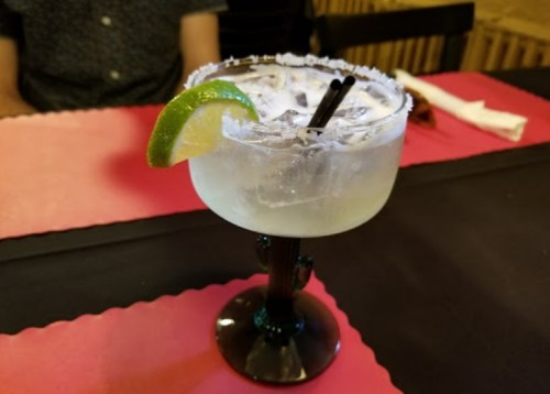 A refreshing cocktail in a cactus-shaped glass, garnished with a lime slice and served with ice.