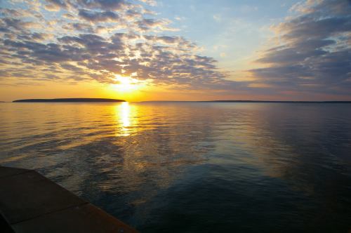 A serene sunset over calm waters, with colorful clouds reflecting on the surface.