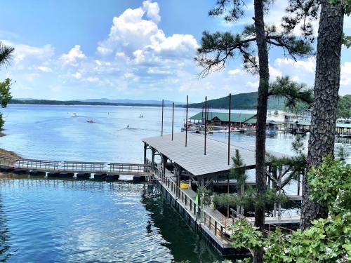 A serene lake view with boats, a dock, and trees under a blue sky with fluffy clouds.