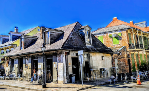 Historic buildings with colorful facades and outdoor seating in a vibrant street scene under a clear blue sky.