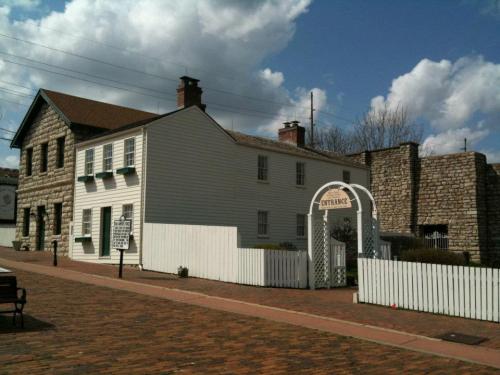 Historic building with a white fence, archway entrance, and stone structure under a blue sky with clouds.