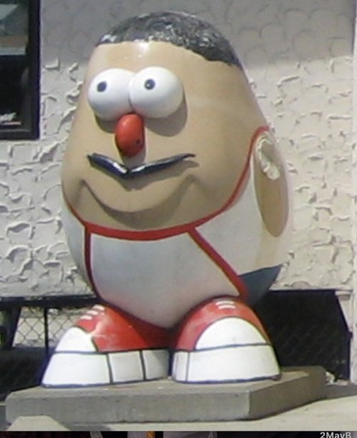 A large, cartoonish potato character with a big smile, wearing a red and white outfit and oversized shoes.